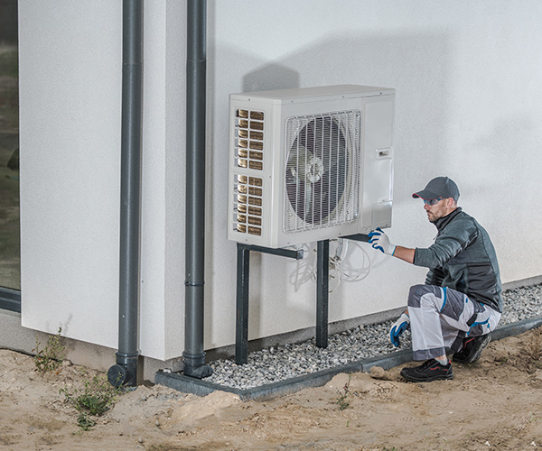 Photo of a man checking the heat pump